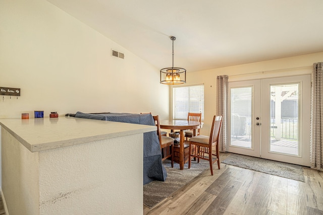 dining area with visible vents, vaulted ceiling, french doors, an inviting chandelier, and light wood-style floors