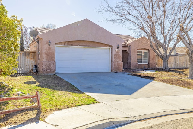 view of front of house with stucco siding, concrete driveway, an attached garage, and fence