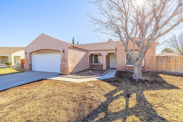 view of front of house with fence, a tile roof, stucco siding, driveway, and an attached garage