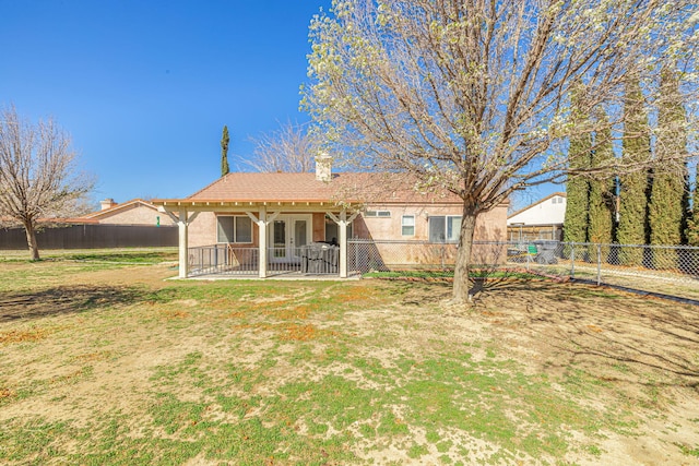 back of house with a patio, a yard, a fenced backyard, stucco siding, and a chimney