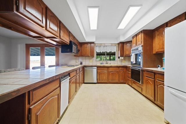 kitchen featuring french doors, sink, tile countertops, white appliances, and decorative backsplash