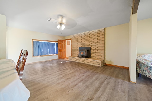 unfurnished living room featuring ceiling fan, light wood-type flooring, and a wood stove