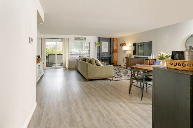 living area featuring light wood finished floors, a fireplace, and baseboards