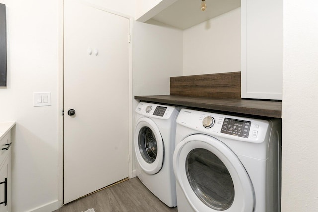 laundry area featuring cabinet space, light wood-style floors, and independent washer and dryer