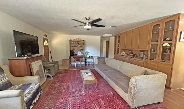 living room with ceiling fan, hardwood / wood-style floors, and a textured ceiling