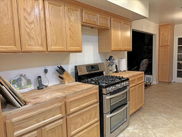 kitchen featuring light brown cabinetry, wooden counters, light tile patterned floors, and double oven range