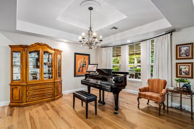 misc room featuring an inviting chandelier, light hardwood / wood-style floors, and a tray ceiling