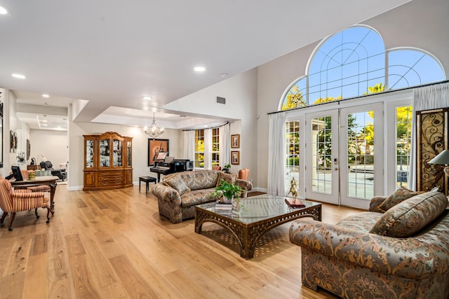 living room featuring light wood-type flooring, french doors, and a chandelier