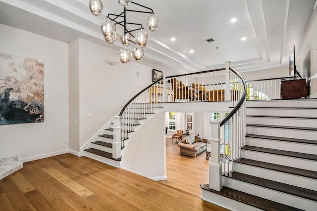 stairs with a chandelier, hardwood / wood-style flooring, and a tray ceiling