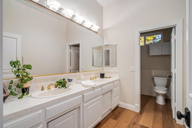 bathroom featuring vanity, toilet, wood-type flooring, and tile walls