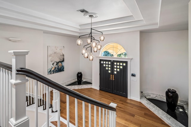 foyer featuring a tray ceiling, hardwood / wood-style floors, and an inviting chandelier