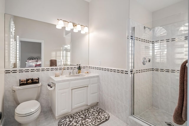 bathroom with walk in shower, vanity, tile walls, tile patterned flooring, and toilet