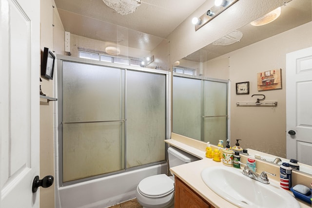 full bathroom with combined bath / shower with glass door, vanity, tile patterned floors, and toilet