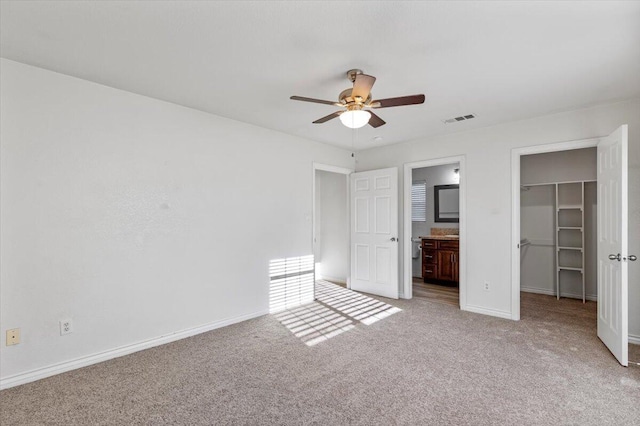 unfurnished bedroom featuring baseboards, visible vents, light colored carpet, a spacious closet, and a closet