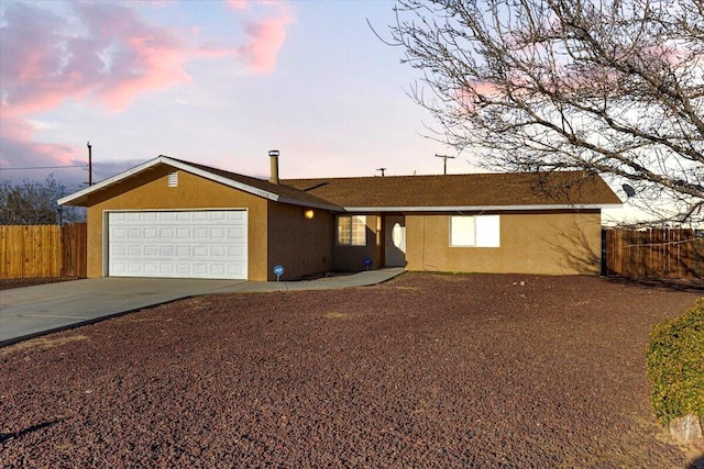 ranch-style house featuring a garage, concrete driveway, fence, and stucco siding