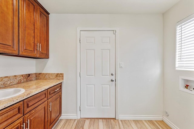 laundry room with washer hookup, a sink, baseboards, cabinet space, and light wood finished floors