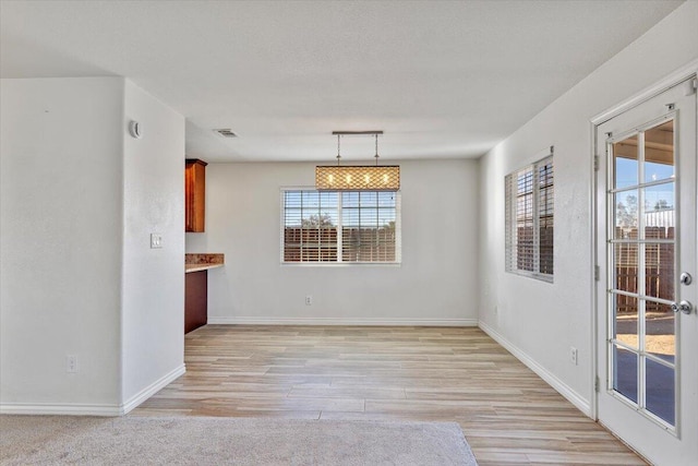 unfurnished room featuring light wood finished floors, baseboards, visible vents, and a textured ceiling