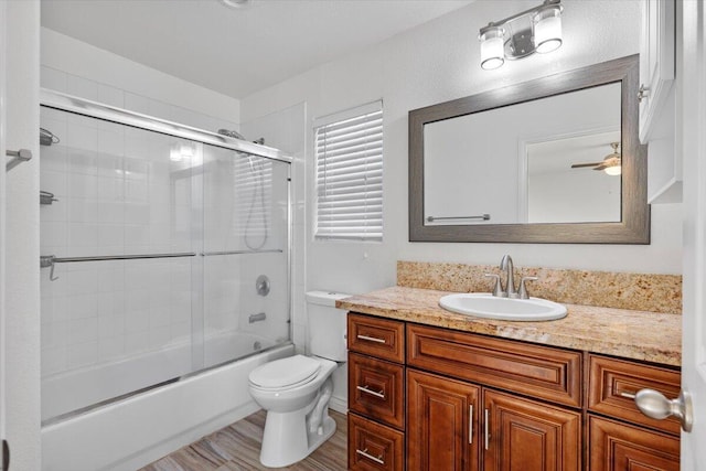 full bath featuring combined bath / shower with glass door, vanity, toilet, and wood finished floors