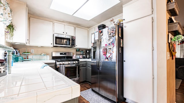 2839 Minford St, Lancaster, CA 93536 - kitchen featuring stainless steel appliances, tile countertops, dark wood-style flooring, and white cabinetry