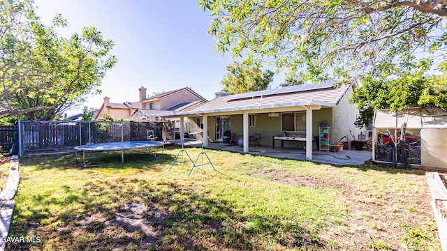 2839 Minford St, Lancaster, CA 93536 - back of property featuring a trampoline, a patio area, roof mounted solar panels, stucco siding, and a fenced backyard