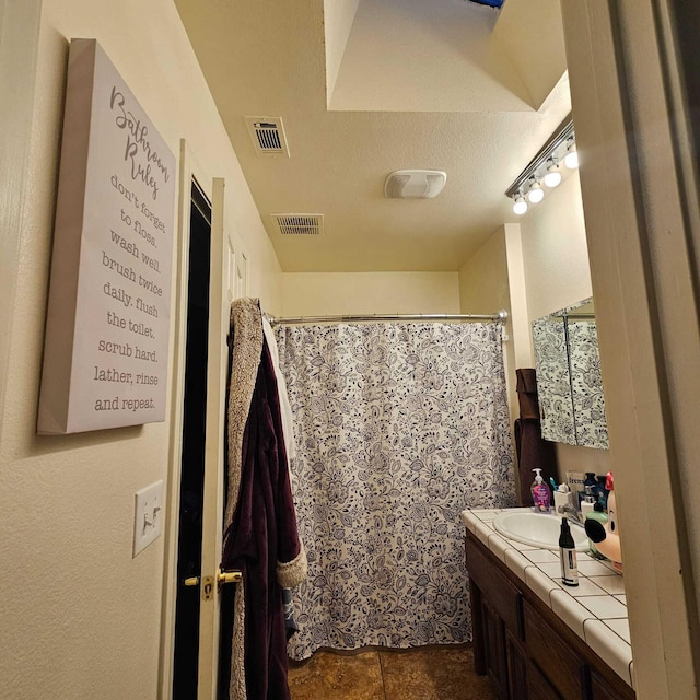 bathroom with a textured ceiling, vanity, and a shower with curtain