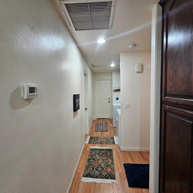 hallway with washer and dryer and light hardwood / wood-style flooring