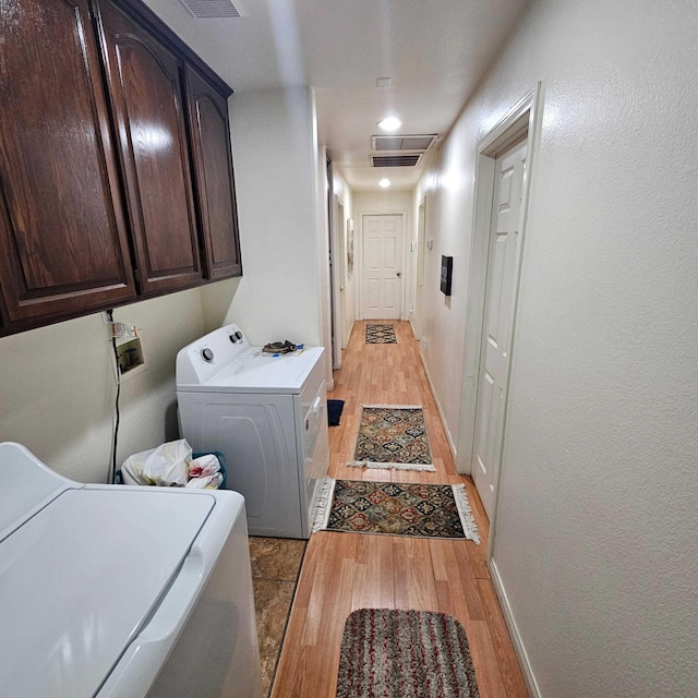 laundry room with cabinets, washer and clothes dryer, and light hardwood / wood-style flooring