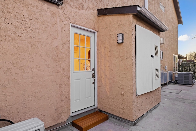 view of exterior entry featuring central air condition unit