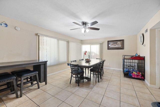 tiled dining room with ceiling fan and a textured ceiling