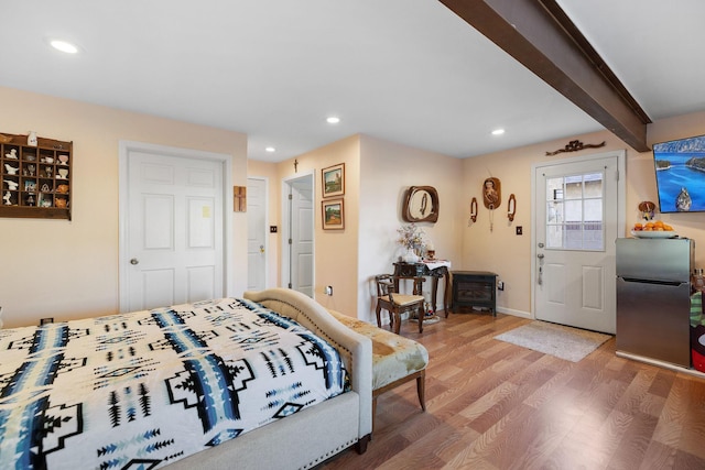 bedroom with hardwood / wood-style flooring, beamed ceiling, and stainless steel refrigerator