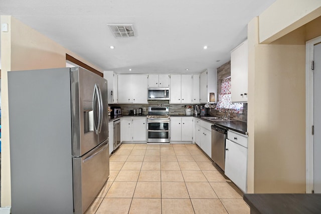 44627 E 11th St, Lancaster, CA 93535 - kitchen featuring stainless steel appliances, dark countertops, light tile patterned floors, decorative backsplash, and white cabinetry