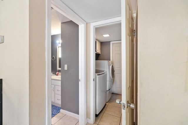 laundry room with light tile patterned flooring, cabinets, and washing machine and dryer