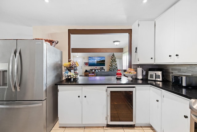 kitchen featuring beverage cooler, light tile patterned floors, backsplash, stainless steel fridge, and white cabinets