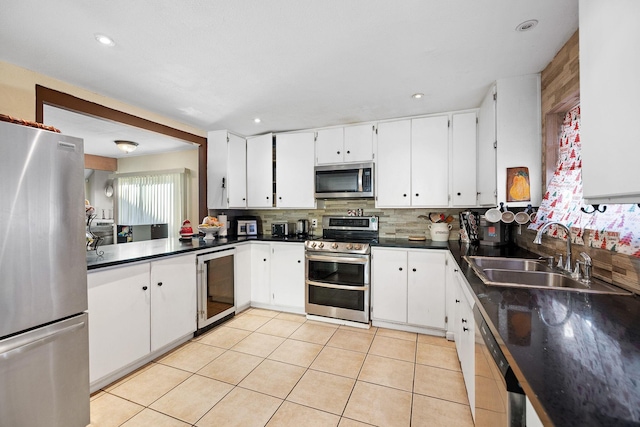 kitchen featuring sink, stainless steel appliances, beverage cooler, white cabinets, and light tile patterned flooring