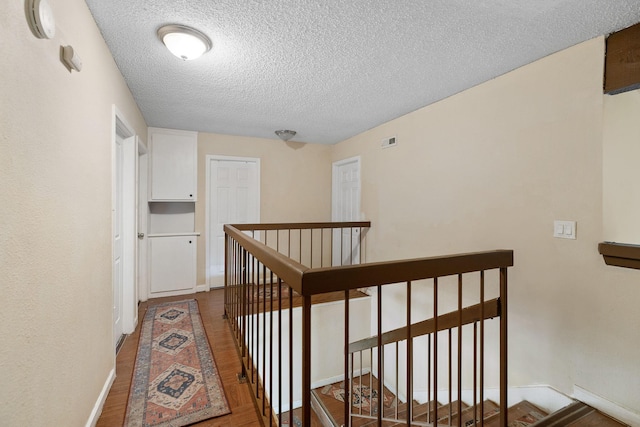 hallway featuring wood-type flooring and a textured ceiling