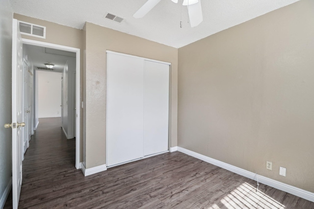 unfurnished bedroom with a closet, dark wood-style flooring, and visible vents
