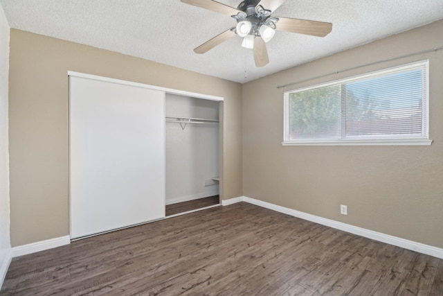 unfurnished bedroom featuring a textured ceiling, a ceiling fan, baseboards, wood finished floors, and a closet