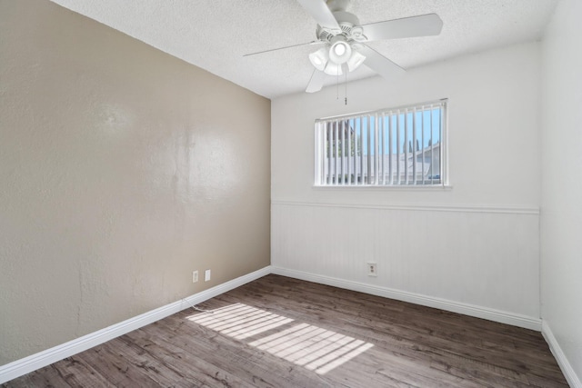 empty room featuring a textured ceiling, baseboards, a ceiling fan, and wood finished floors