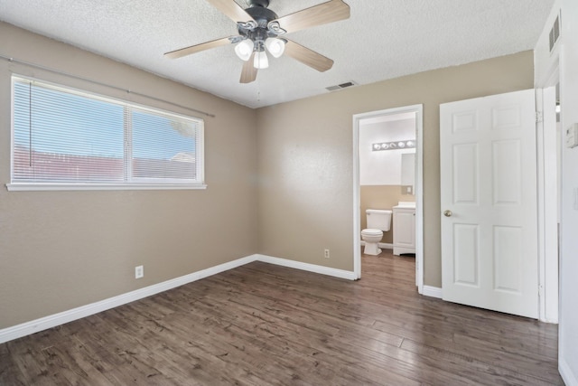 unfurnished bedroom with baseboards, a textured ceiling, wood finished floors, and visible vents
