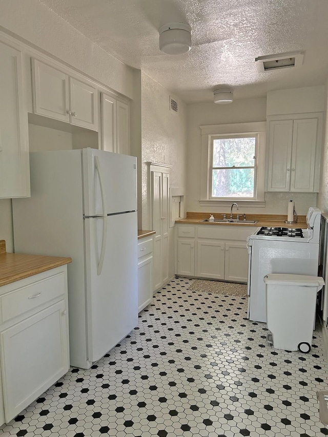 kitchen featuring white cabinets, a textured ceiling, white appliances, and sink