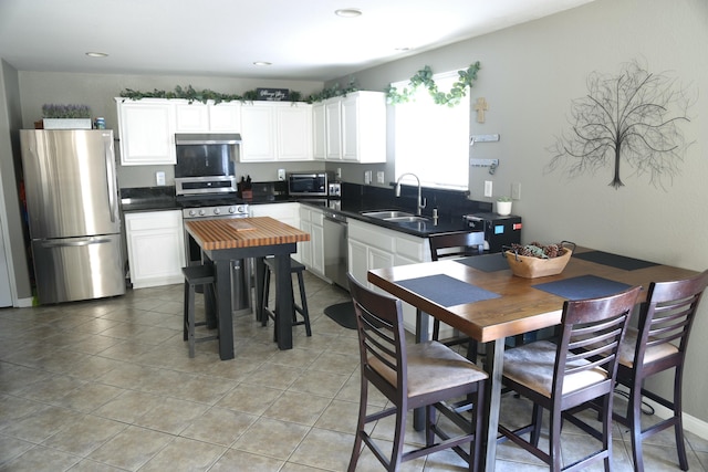 kitchen featuring white cabinets, appliances with stainless steel finishes, sink, and light tile patterned floors