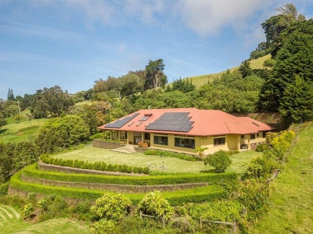65-1104 Hokuula Rd, Kamuela, HI 96743 - rear view of house with roof mounted solar panels and a yard
