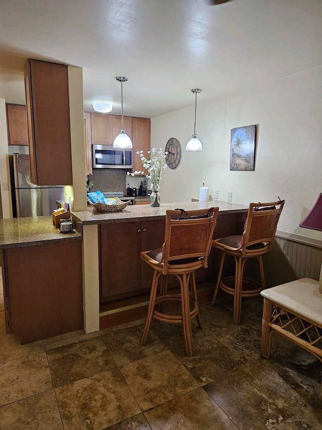 525 Aleka Lp Unit K3, Kapaa, HI 96746 - kitchen with stainless steel appliances, a peninsula, hanging light fixtures, stone counters, and a breakfast bar area