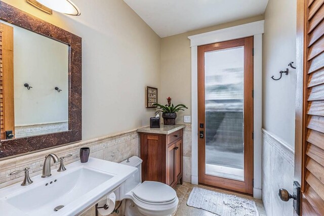 5070 Kukuna Rd, Anahola, HI 96746 - bathroom with a sink, a wainscoted wall, toilet, and tile walls