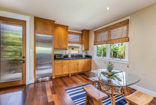 5070 Kukuna Rd, Anahola, HI 96746 - kitchen with built in refrigerator, a sink, dark countertops, dark wood-style floors, and baseboards