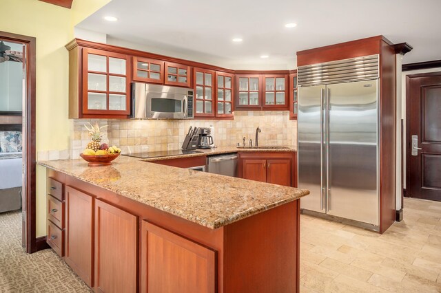 4-820 Kuhio Hwy Unit C402, Kapaa, HI 96746 - kitchen featuring appliances with stainless steel finishes, a sink, a peninsula, backsplash, and light stone counters