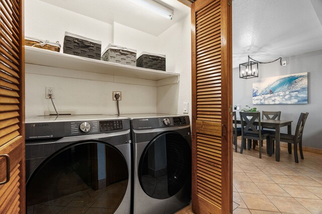 1661 Pee Rd Unit 4105, Koloa, HI 96756 - laundry room featuring washing machine and clothes dryer, light tile patterned flooring, and a chandelier