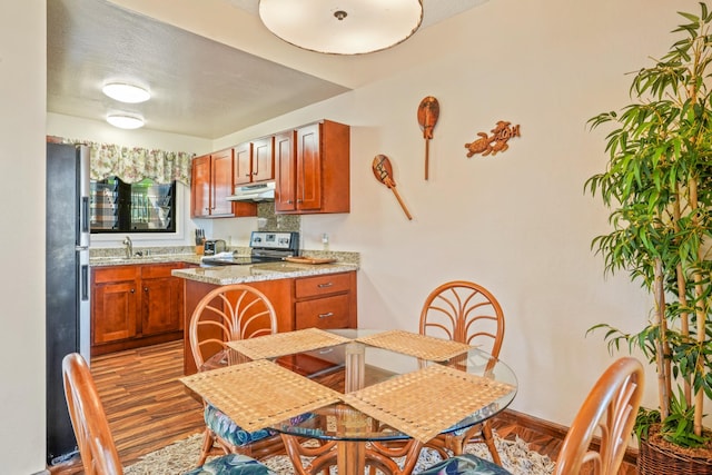 4460 Nehe Rd Unit 203, Lihue, HI 96766 - kitchen featuring under cabinet range hood, electric range, freestanding refrigerator, wood finished floors, and a peninsula