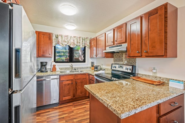 4460 Nehe Rd Unit 203, Lihue, HI 96766 - kitchen with appliances with stainless steel finishes, under cabinet range hood, a sink, light wood finished floors, and a peninsula