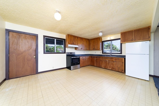 127 Kanoelani St Unit 1, Hilo, HI 96720 - kitchen featuring freestanding refrigerator, stainless steel electric range oven, under cabinet range hood, dark countertops, and baseboards
